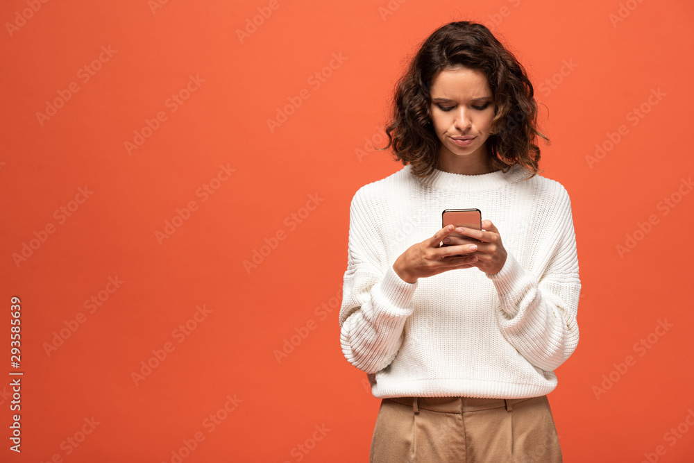 woman in autumnal outfit using smartphone isolated on orange woman in autumnal outfit using smartphone isolated on orange