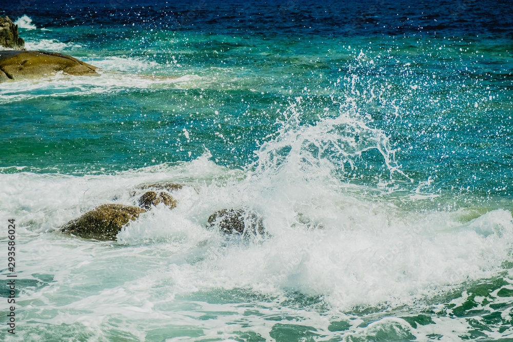Splash of sea water waves hitting the rocky beach
