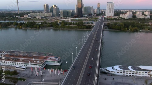 Vienna, Austria, aerial tilt up shot of cityscape showing bridge over the Danube river and modern skyscrapers at the Vienna International Centre at sunset. photo