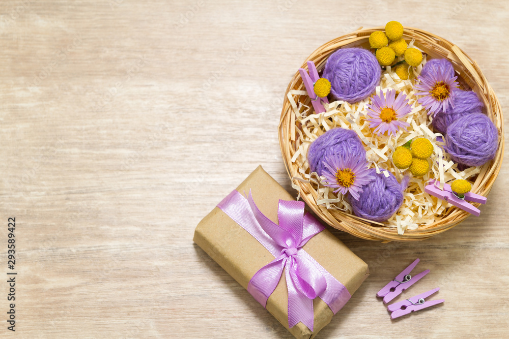 Balls of thread in a straw basket on a wooden table. Mother's day concept. Scenery for Valentine's Day. Vibes of kindness and love Balls of thread in a straw basket on a wooden table. Mother's day concept. Scenery for Valentine's Day. Vibes of kindness and love