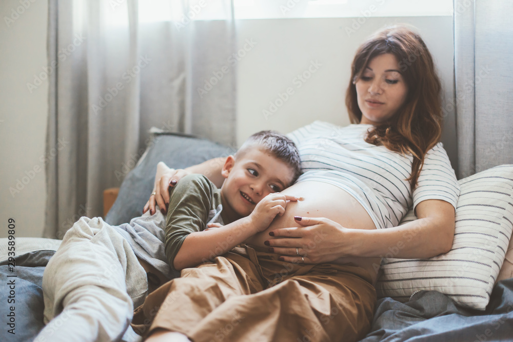Pregnant mom playing with child in bedroom Pregnant mom playing with child in bedroom