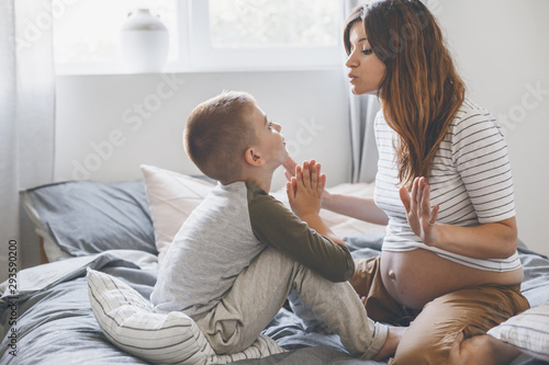 Pregnant mom playing with child in bedroom