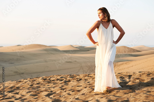 Pretty girl posing in white dress in sand