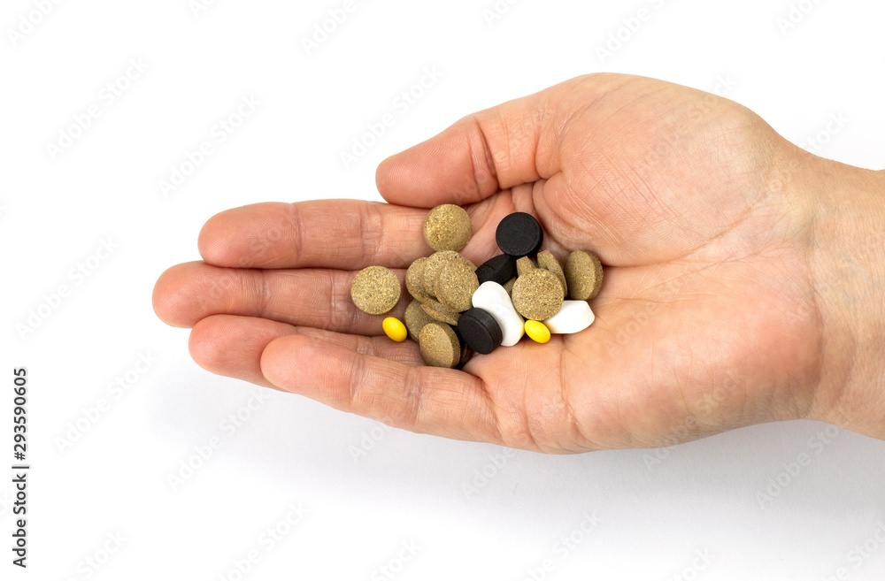 Human hand is holding handful of different pills isolated on white background. Human hand is holding handful of different pills isolated on white background.