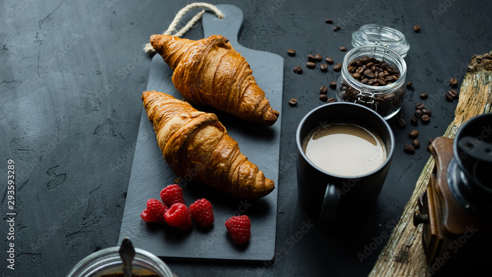 Obraz premium Croissant z malinami leżący na kamiennej desce. Ciemne tło, widok z góry.