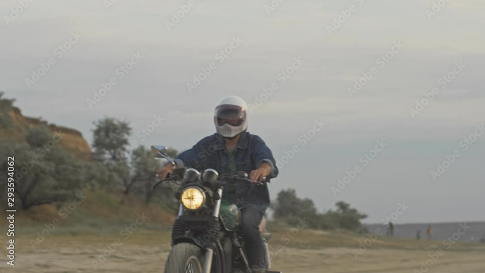 Confident young man in helmet riding motorcycle at the beach Confident young man in helmet riding motorcycle at the beach