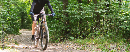 Young athletic cyclist riding down summer woods