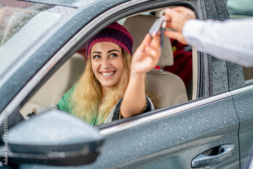 young woman take the key from valet to drive her car photo