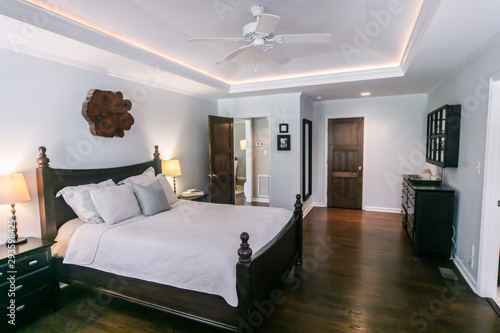 Master bedroom with king size bed and tray ceilings with uplighting and hradwood floors photo