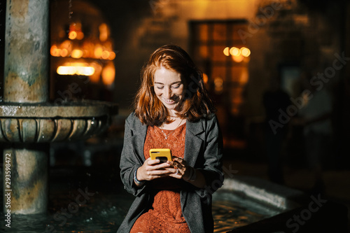 Sant Felip Neri square, Barcelona, a young girl reads mobile by night photo