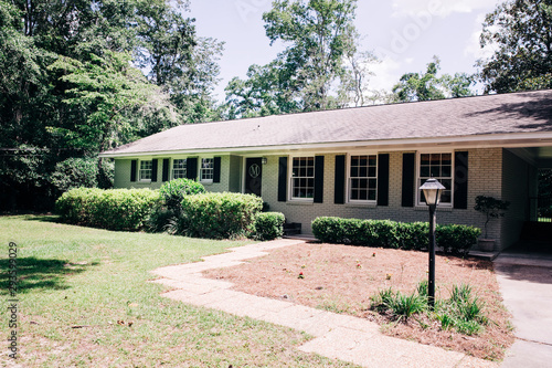 Front view of exterior white cream brick 1950's house with black shutters