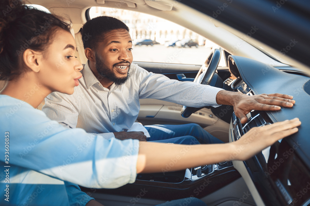 Afro couple at car showroom touching dash of new auto Afro couple at car showroom touching dash of new auto