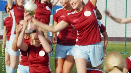 Happy women in soccer sportswear getting Cup, celebrating win and hugging each other