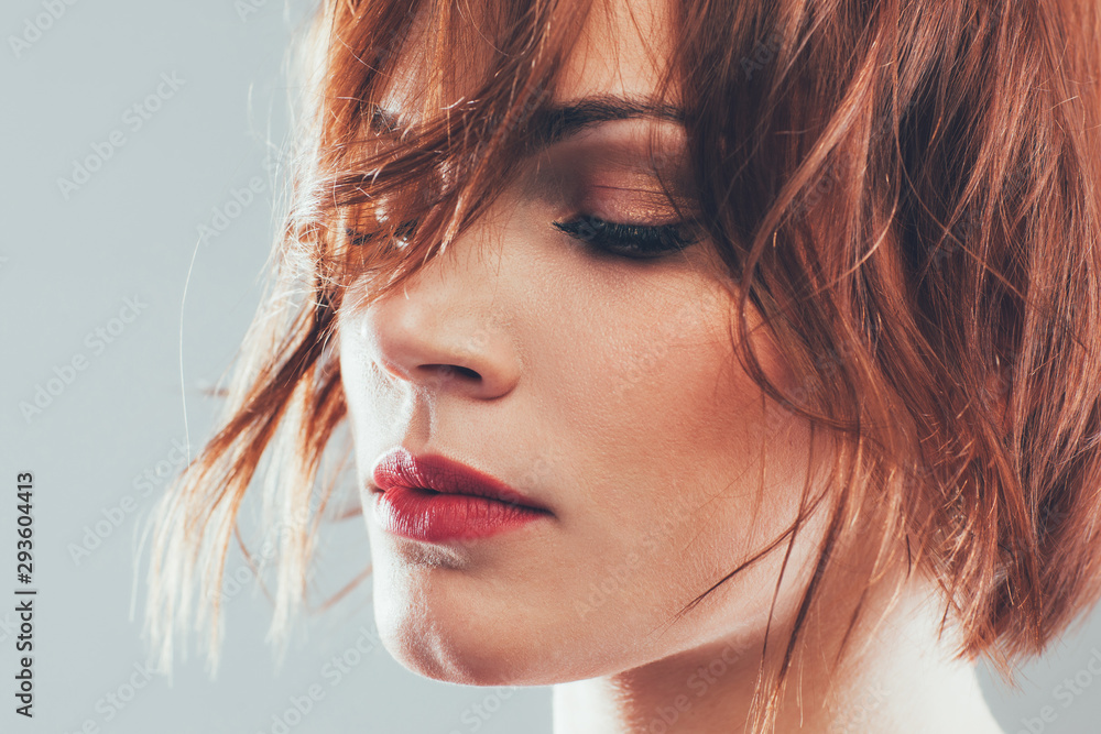 Professional hair studio. Portrait of woman with styled short red hair, eyes closed. Gray background. - obrazy, fototapety, plakaty 