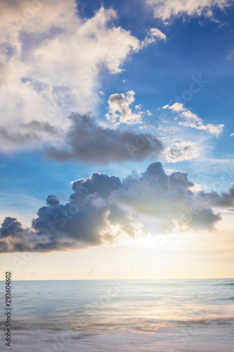 the sun in clouds. the sun shines through the dark gray clouds  the light is reflected in the calm blue sea  a beautiful landscape. Vertical photo.