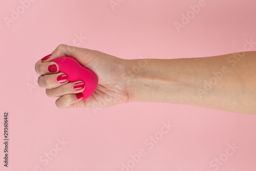 Girl hand holds a beauty makeup blender on a pink background, copy space.