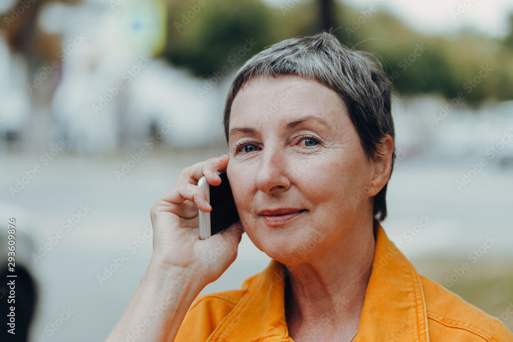 Portrait of a beautiful senior woman. Happy senior woman on the city streets using cellphone. Portrait of a beautiful senior woman. Happy senior woman on the city streets using cellphone.
