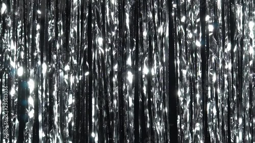 Silver rain from tinsel. Dynamic background in shining lights and sparkling particles. Beautiful silver background with shiny silver glitter sparkles. Festive mood. Christmas or holiday theme