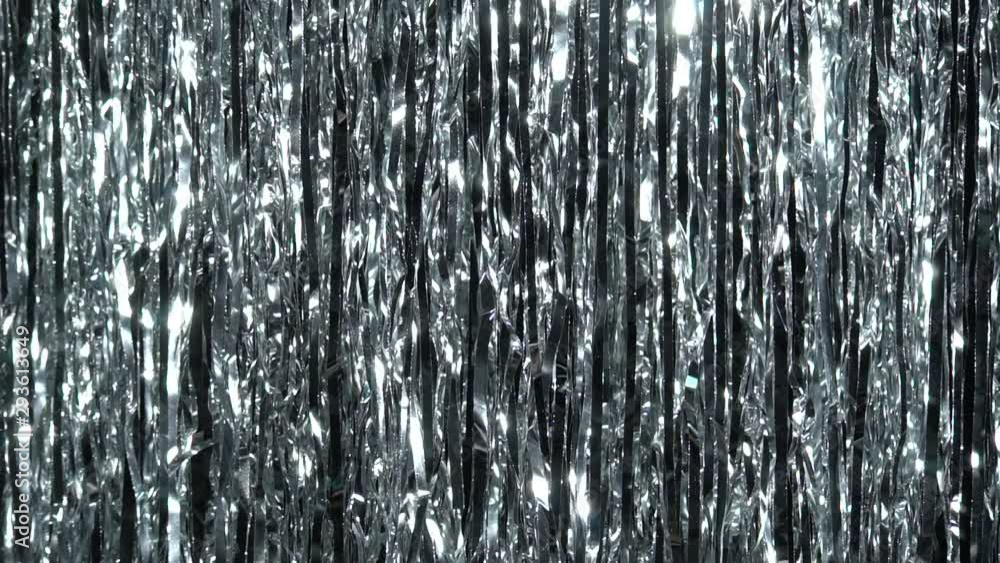 Silver rain from tinsel. Dynamic background in shining lights and sparkling particles. Beautiful silver background with shiny silver glitter sparkles. Festive mood. Christmas or holiday theme Silver rain from tinsel. Dynamic background in shining lights and sparkling particles. Beautiful silver background with shiny silver glitter sparkles. Festive mood. Christmas or holiday theme