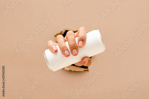 The hand hold a can through the broken wall
