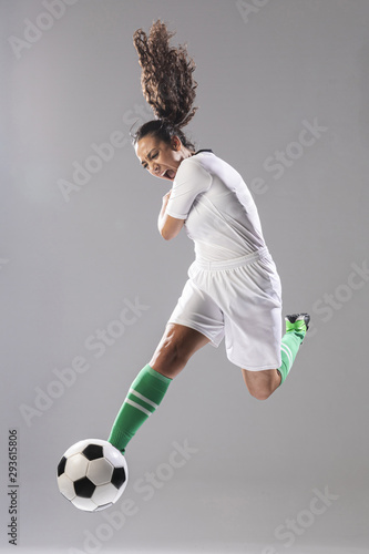 Young woman kicking soccer ball
