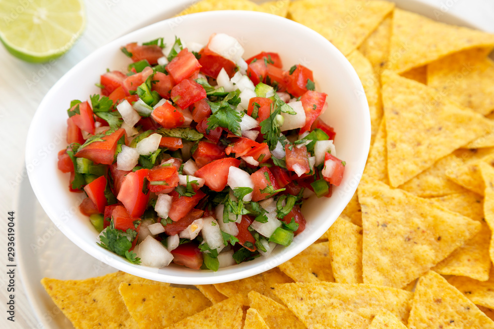 Pico de Gallo with gluten free tortilla chips on a white wooden table, side view. Close-up. Pico de Gallo with gluten free tortilla chips on a white wooden table, side view. Close-up.