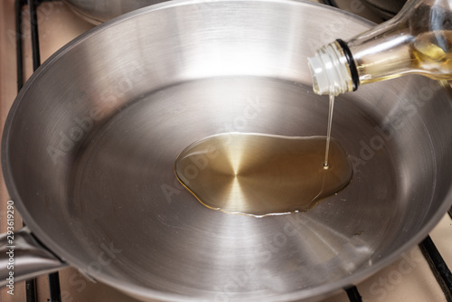 Olive oil is poured onto a stainless steel pan