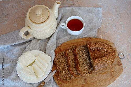 cup of tea, homemade cheese, teapot on a linen napkin, top view
