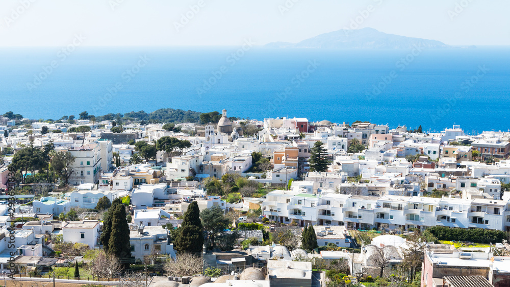 Town of Capri, Italy with white houses, blue sky and blue water. View of Mount Vesuvius