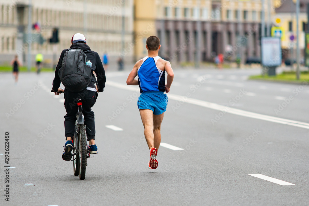 Marathon. Runner and cyclist on a city road. Marathon race