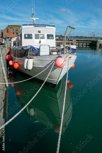 Boat moored in harbour with reflection