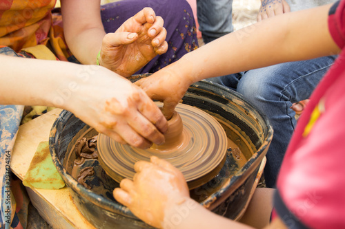 A close up view on ceramic production process on potter's wheel with children. Clay crafts with kids concept.