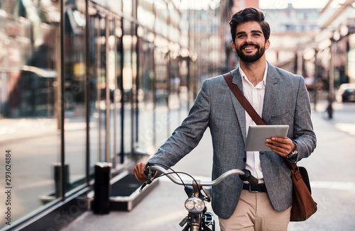 Smiling businessman using tablet on the way to office. Business, education, lifestyle concept photo