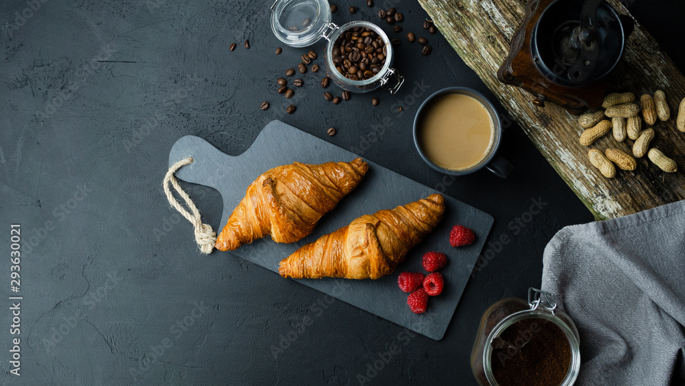Rogale croissant leżące na ciemnej desce w otoczeniu malin i kawy. Ciemne tło, widok z góry. - obrazy, fototapety, plakaty 
