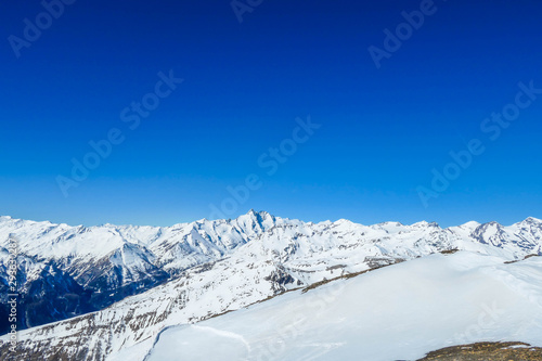 A beautiful and serene landscape of mountains covered with snow. Thick snow covers the slopes. Clear weather. Sharp slopes of the mountains covered with snow, with partially visible rocks. © Chris