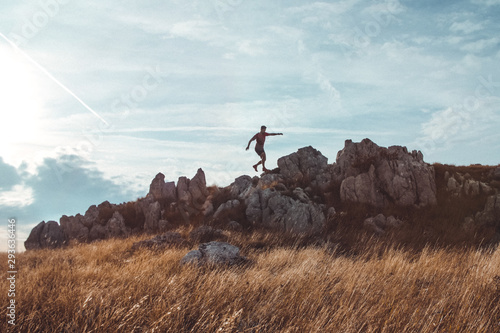 Young man walking across the mountains ridge. Trail running preparations. Sunset