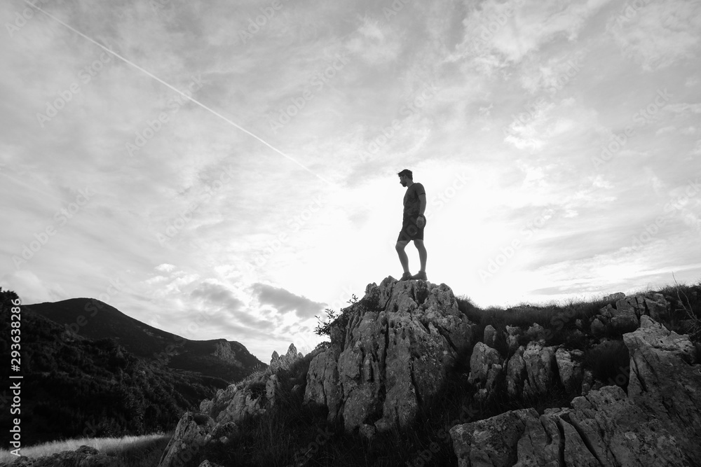 Young athletic man standing on the ridge. Trail running preparations for race.