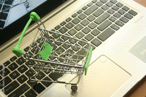 A mini dummy shopping trolley on a lapptop keyboard as a concept for online shopping, saving, business and making money as well as running a business. photo