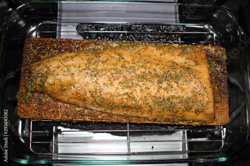 Canvas Print Baked cedar plank salmon on a glass baking tray resting on the stove top