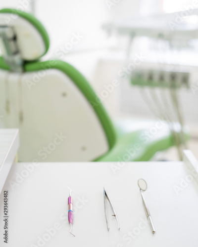 Sterile instruments lie on a table in the dentist office. A mirror, tweezers and a probe are on the doctor table. Oral hygiene, caries prevention, examination.