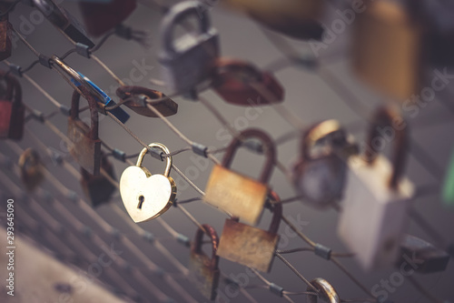 Lock for couple for making a promise to love forever. Master keys hanging on the rails of bridge, Symbolic love locks hang along the bridge. Vintage filter. Soft f.ocus on the golden heart lock. photo