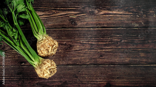 Obraz na plátně Celeriac (turnip rooted celery) roots with green leaves on dark wooden rustic bo