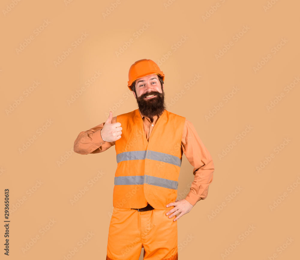 Builder shows thumb up. Construction worker in hardhat. Business, building, industry concept. Builder in hard hat. Bearded man in overalls. Mechanical worker. Industrial worker in construction helmet.