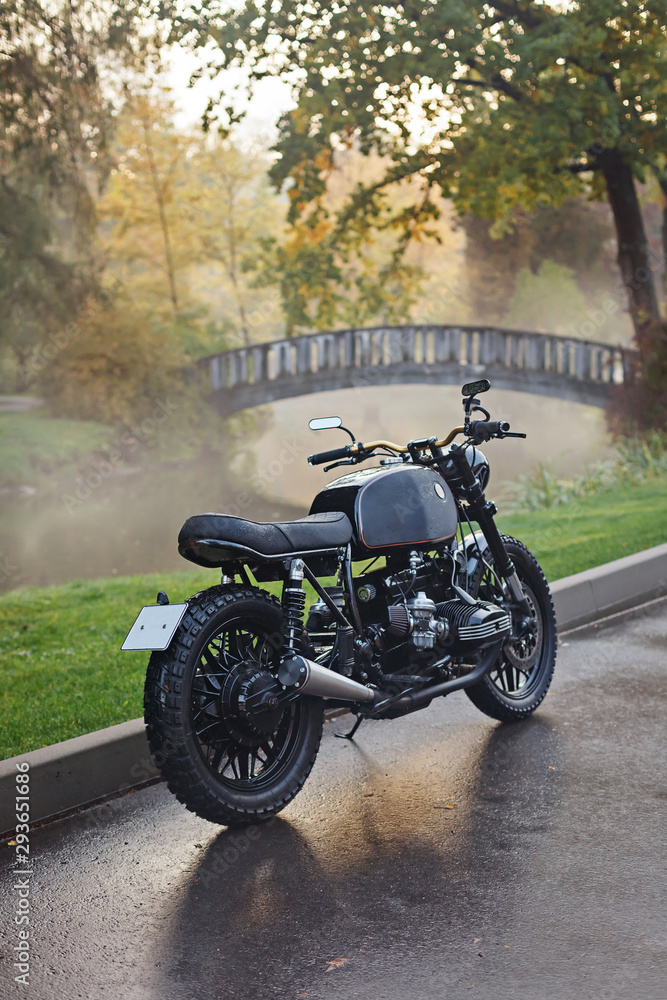 Classic motorcycle parked on wet asphalt in a foggy autumn park