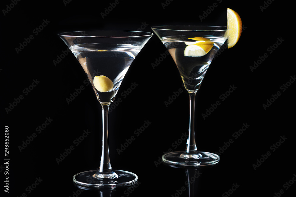 Martini Glasses with olive and lemon piece on a black background. Selective focus. Martini Glasses with olive and lemon piece on a black background. Selective focus.