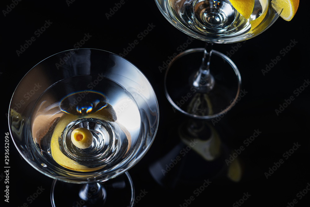Martini Glasses with olive and lemon piece on a black background. Selective focus. Close up. Martini Glasses with olive and lemon piece on a black background. Selective focus. Close up.