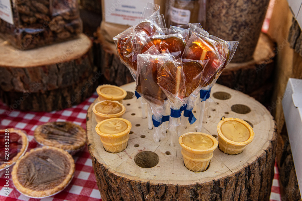 Sweet treats at local farmer's market. A closeup view of handmade lollipops and confectionary displayed in rustic wooden stands on a market stall during a fair for local cottage industries.