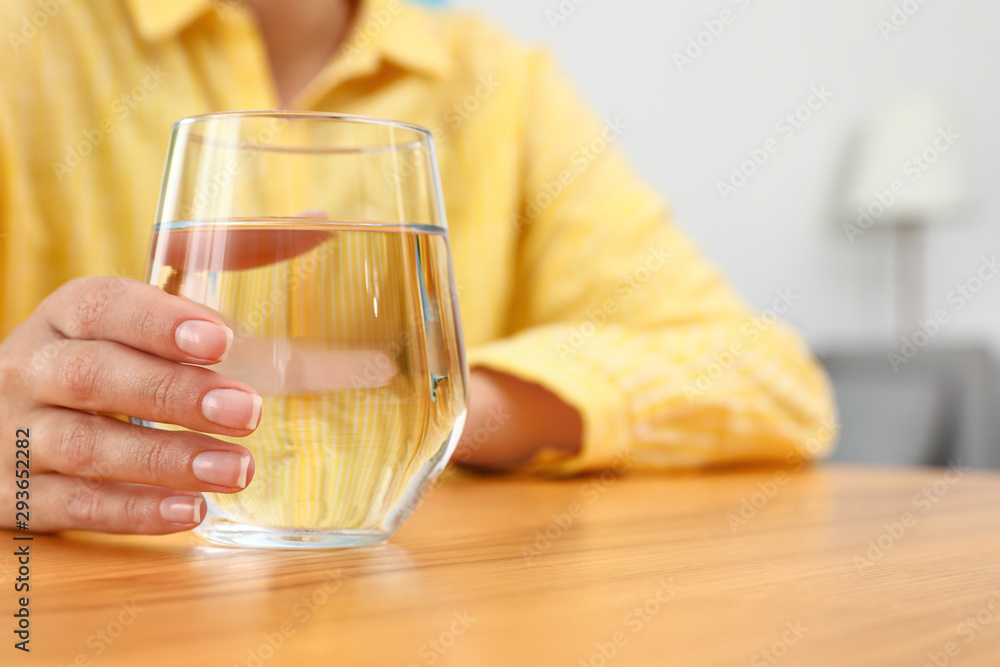 Woman holding glass of water at wooden table, closeup with space for text. Refreshing drink Woman holding glass of water at wooden table, closeup with space for text. Refreshing drink