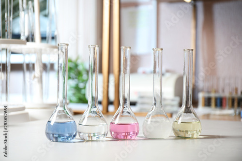 Glassware with colorful liquids on table indoors. Laboratory analysis © New Africa