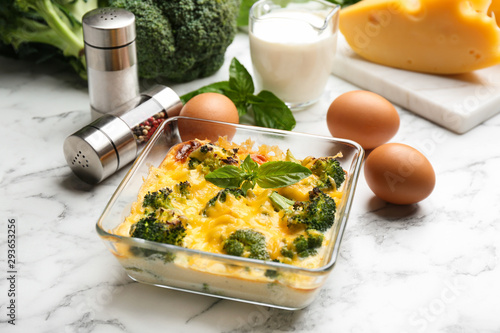 Tasty broccoli casserole in baking dish on white marble table